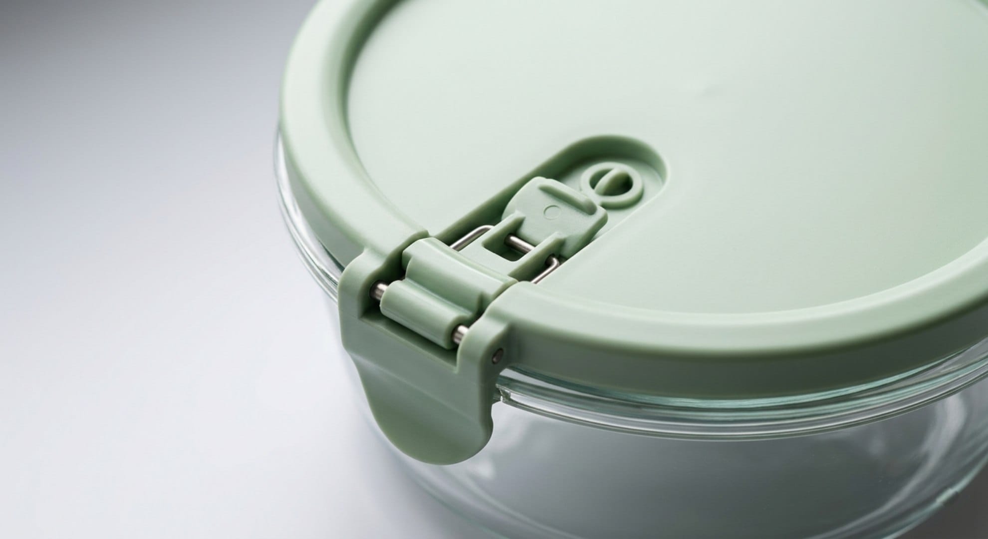Close-up of an airtight latch lid on a round glass meal prep container showing the sealing mechanism